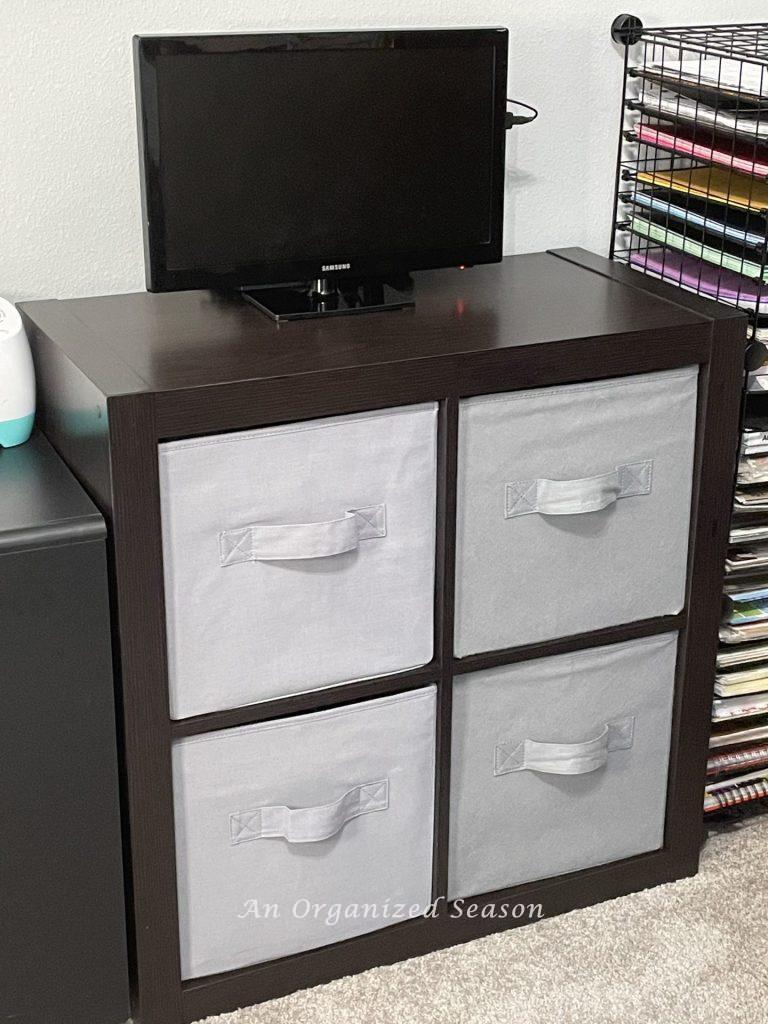 A brown modular storage unit filled with four gray fabric cubes, showing ideas to organize a craft space.