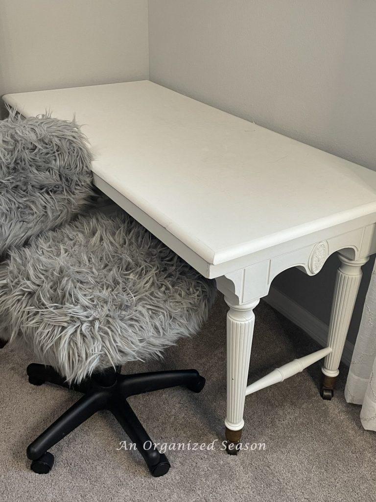 A white craft desk with gray furry office chair, showing ideas to organize a craft space.