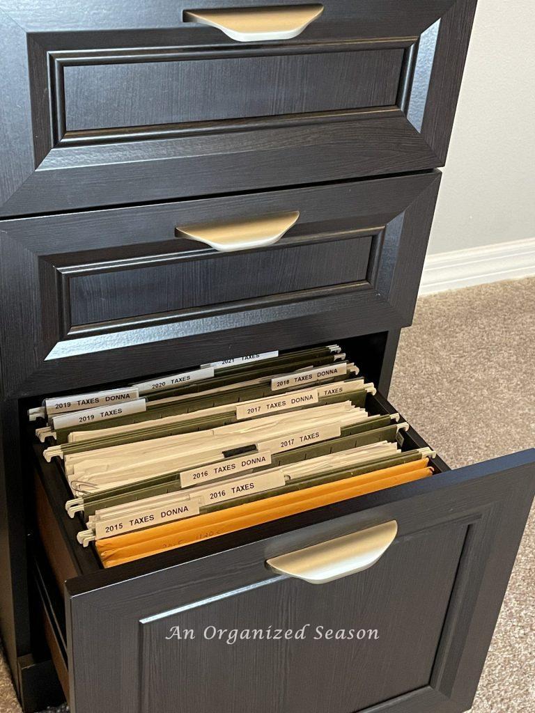 A black file cabinet with tax files showing how to get rid of paper clutter.