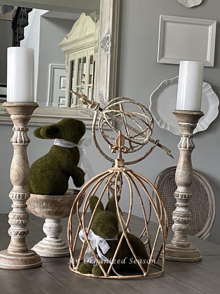 Two moss bunnies, metal pieces, and wood candlesticks are the centerpiece of my nature-inspired Easter tablescape.
