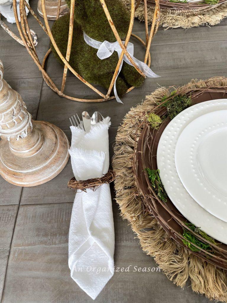 White napkin with eating utensils wrapped in a twig napkin holder are perfect for this nature-inspired Easter tablescape.