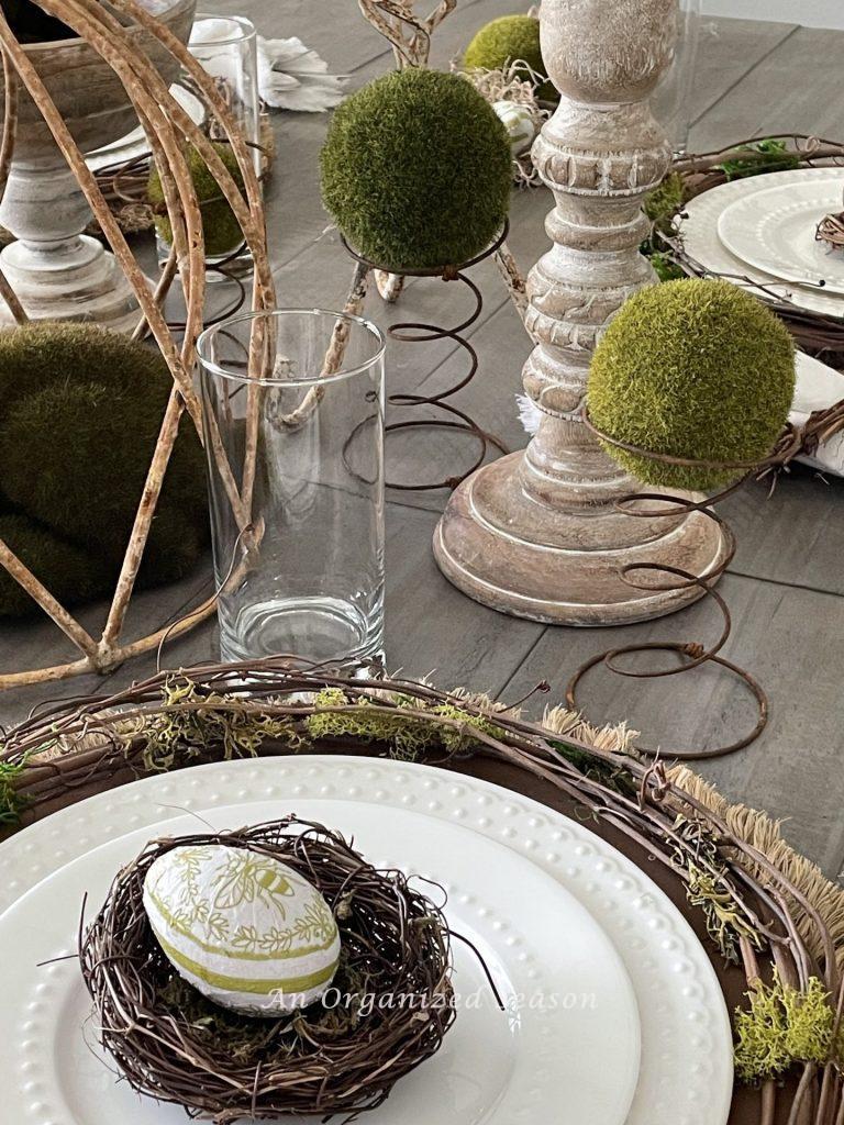 An Easter egg resting in a nest on a place setting looks pretty in this nature-inspired Easter tablescape.