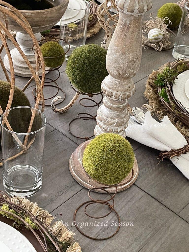 Moss spheres resting in a rusty mattress spring add interest to this nature-inspired Easter tablescape.