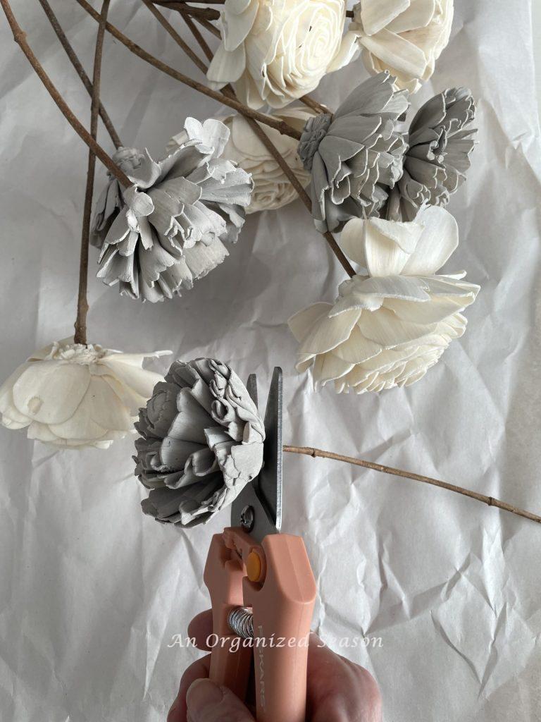 Pruners cutting the stem off a wood flower to be used to  create a wood flower wreath.