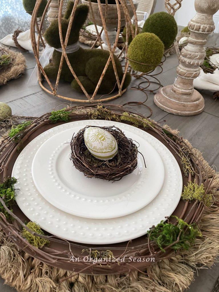 A white place setting with a nest and decoupage egg, an idea to decorate your home for Spring.