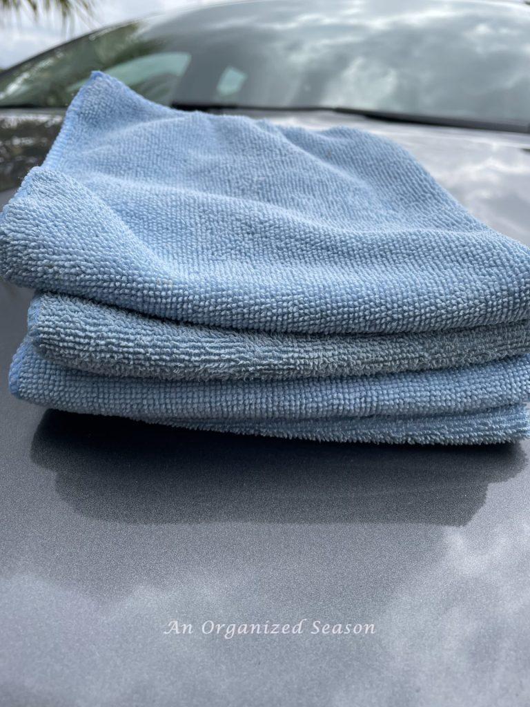 A stack of four blue microfiber cloths to be used to clean a car. A strategy to clean and organize a car.