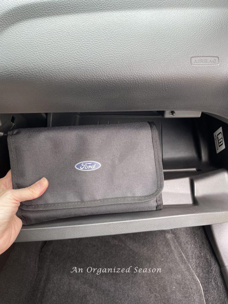 A black pouch that holds car license and registration in a glove compartment, an example of a  strategy to clean and organize a car.