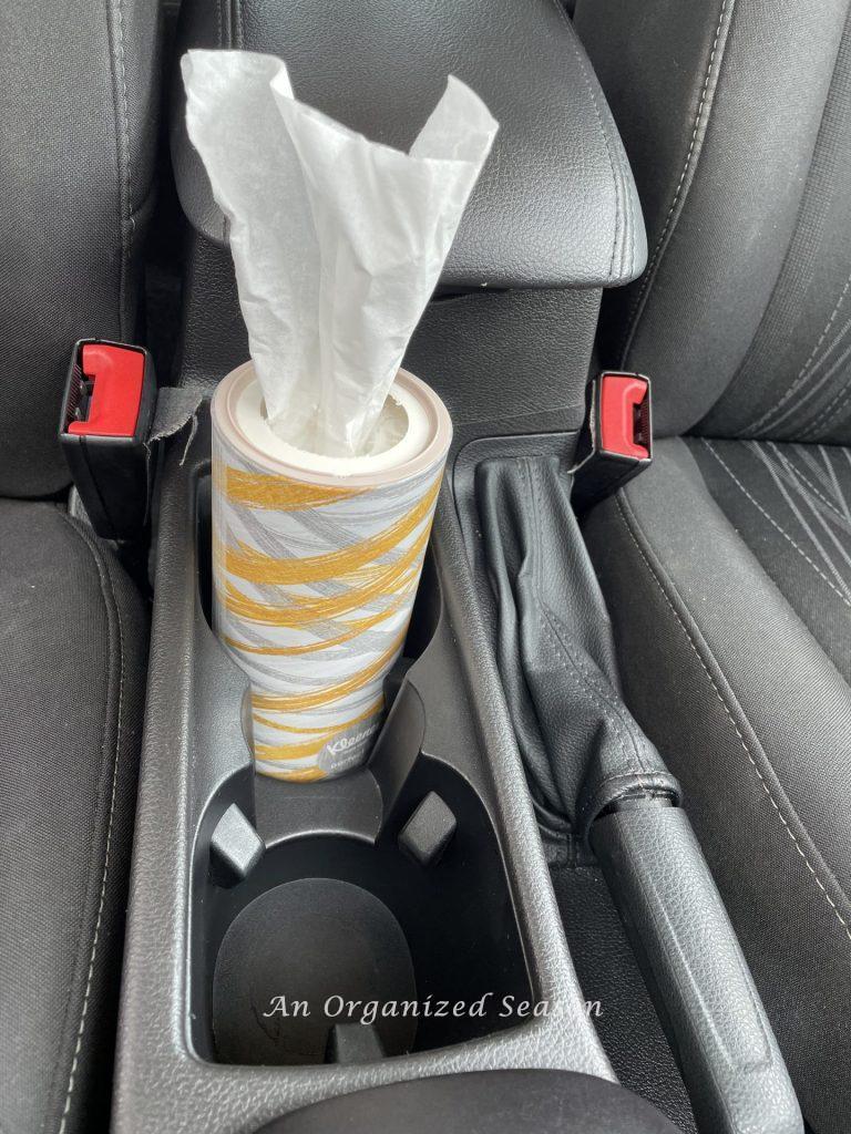 A round tissue holder that fits in a car cup holder, an example of a strategy to clean and organize a car.