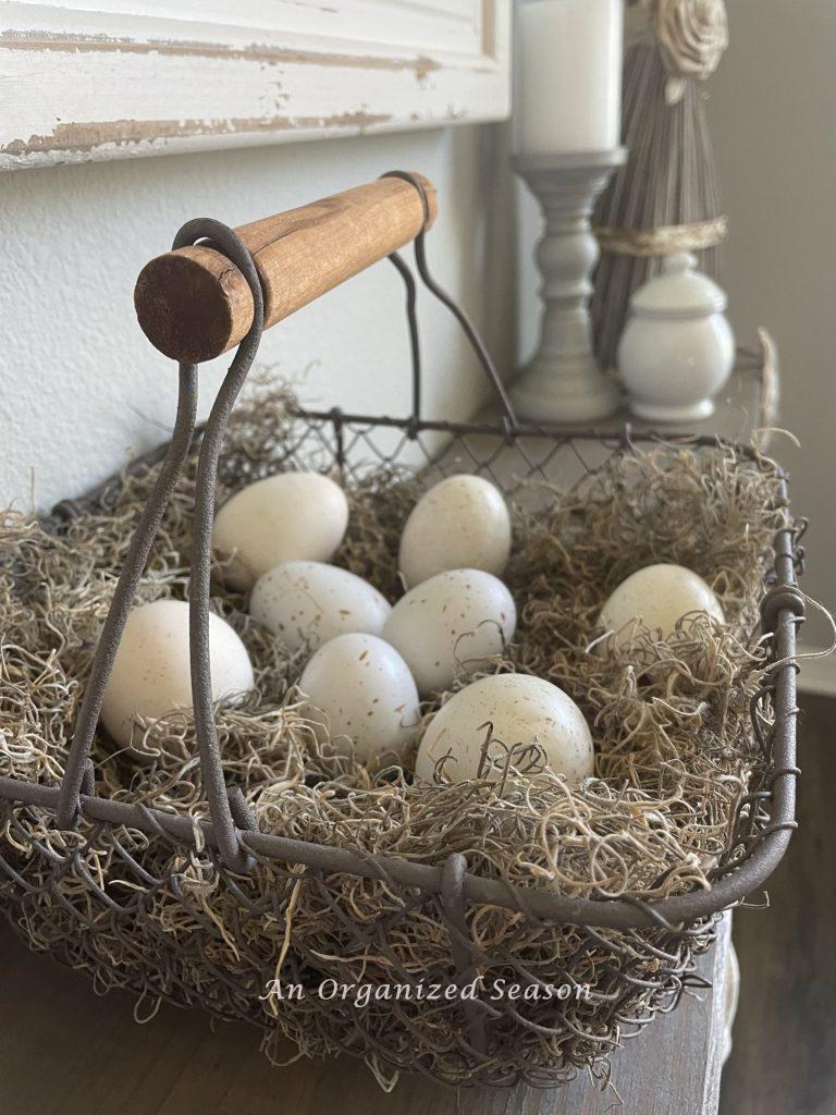 White speckled eggs in a wire basket on a nest of moss, an idea to decorate your home for Spring.