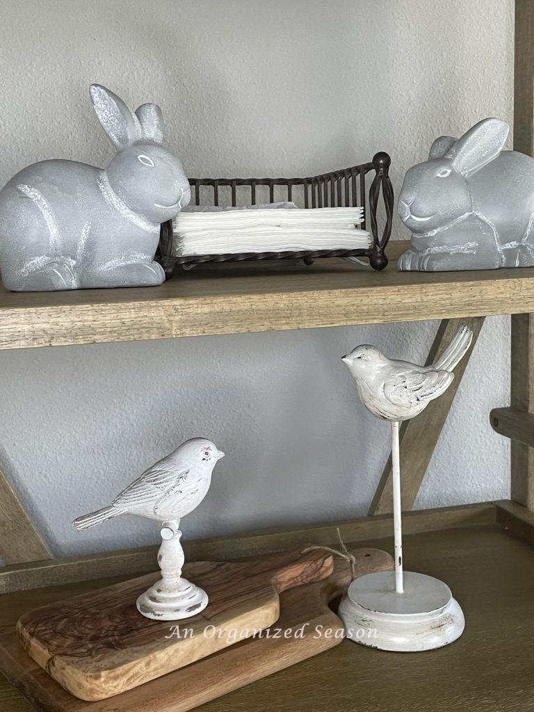 Two gray bunnies on a shelf above two white birds showing ideas to decorate your home for Spring.