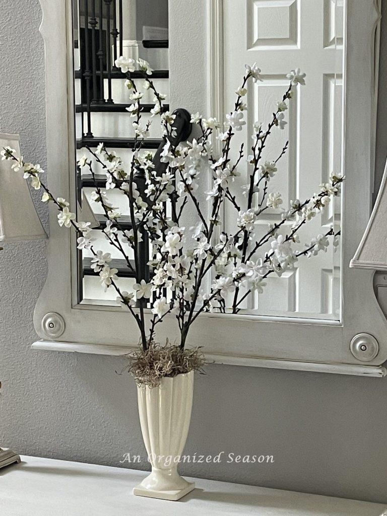 White flowering branches in a cream vase, an example of ideas to decorate your home for Spring.