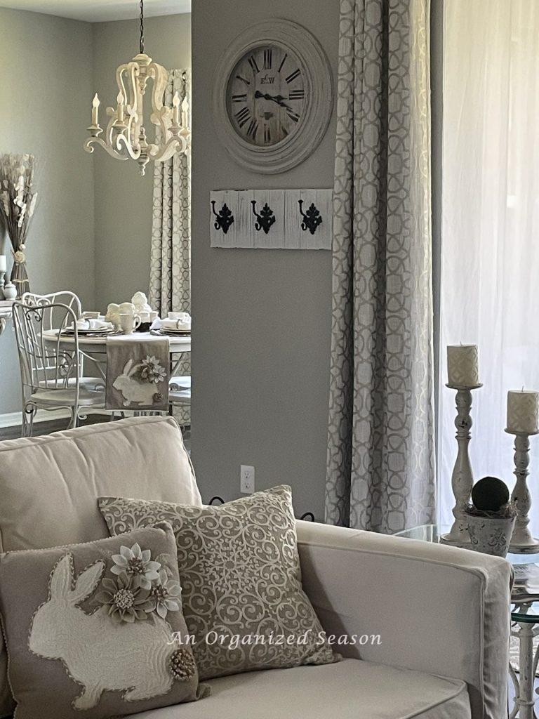 A bunny pillow in front of an embroidered pillow on a white couch, showing ideas to decorate your home for Spring.
