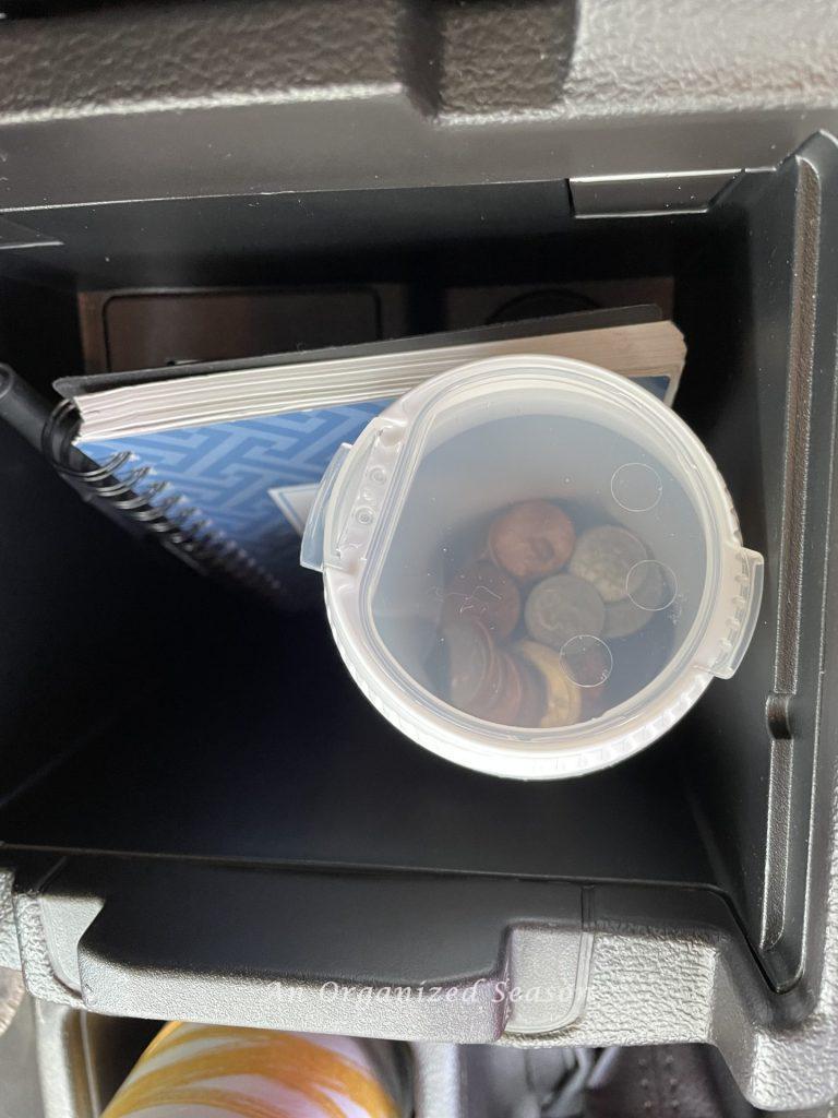 Loose change stored in a gum container in the car console, an example of a  strategy to clean and organize a car.