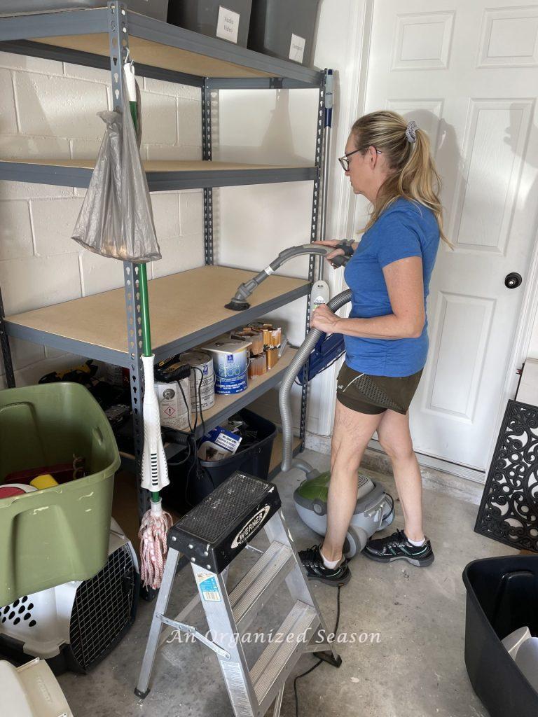 A woman vacuuming shelves in a garage. Showing how to organize a garage into zones.