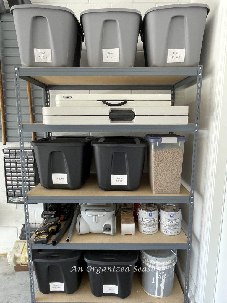 Shelves in a garage organized with black and gray tubs. Showing how to organize a garage into zones.