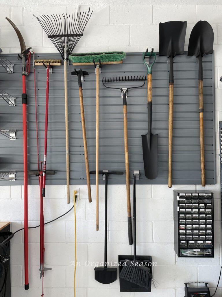 Yard tools neatly organized on a garage wall storage system. Showing how to organize a garage into zones.