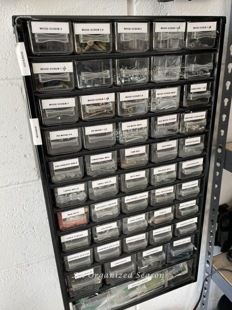 A storage container for hardware attached to a garage wall. Showing how to organize a garage into zones.