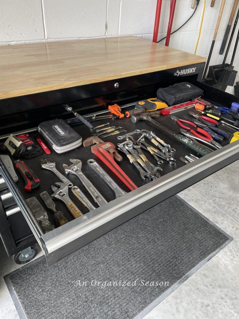 An open drawer of a workbench displays organized hand tools. Showing how to organize a garage into zones.