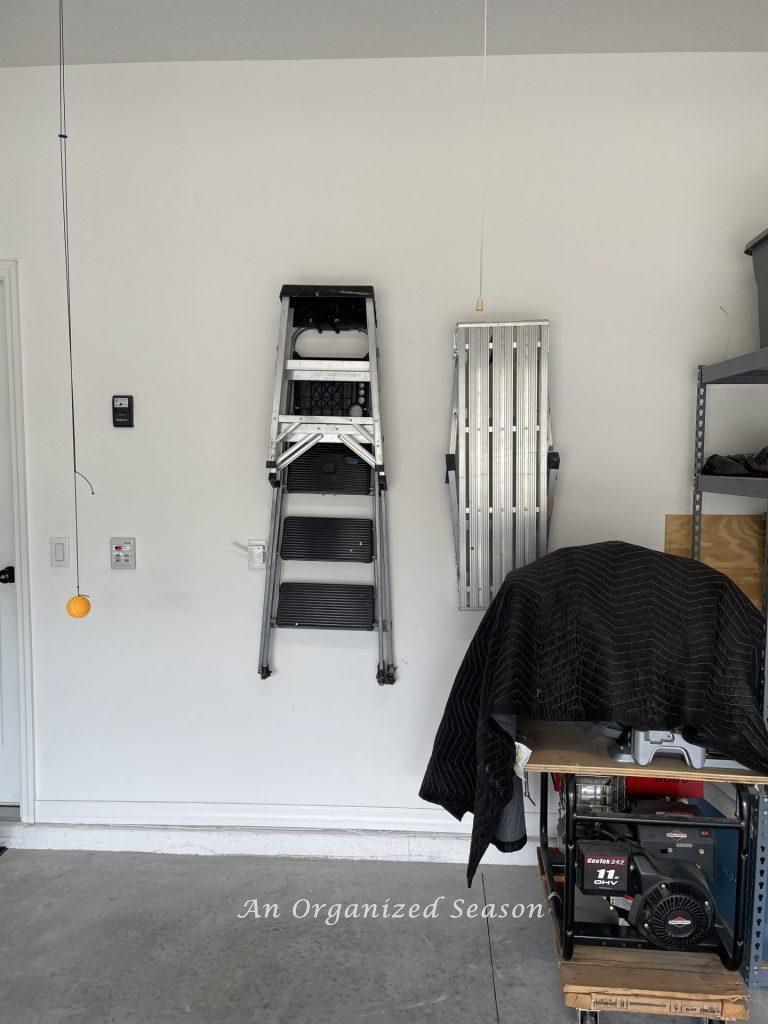 Ladders hanging on hooks on a garage wall. Showing how to organize a garage into zones.