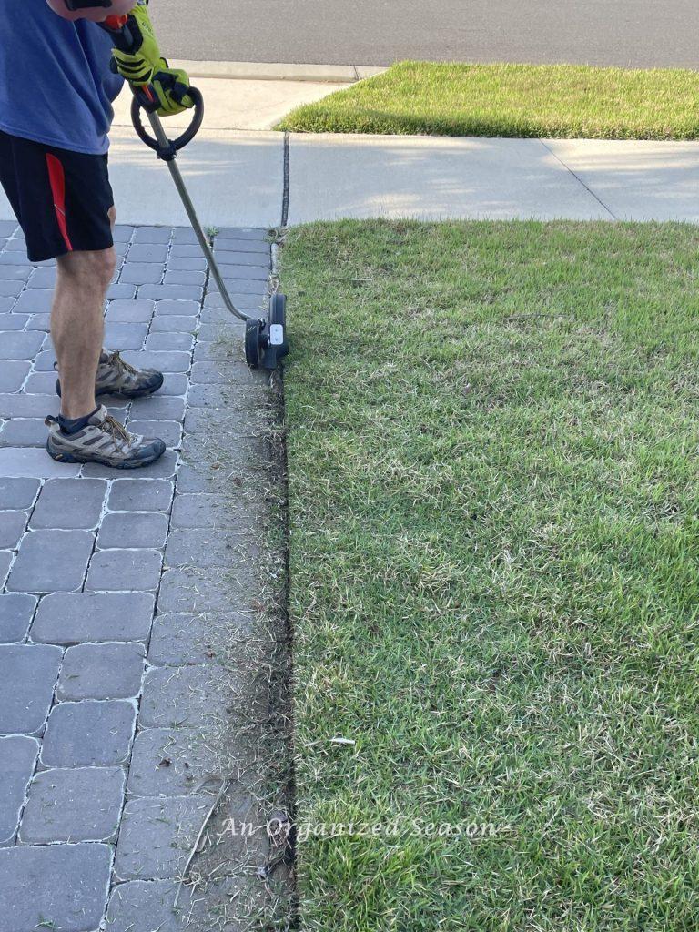 A man edging his driveway, a strategy to improve his home's curb appeal.