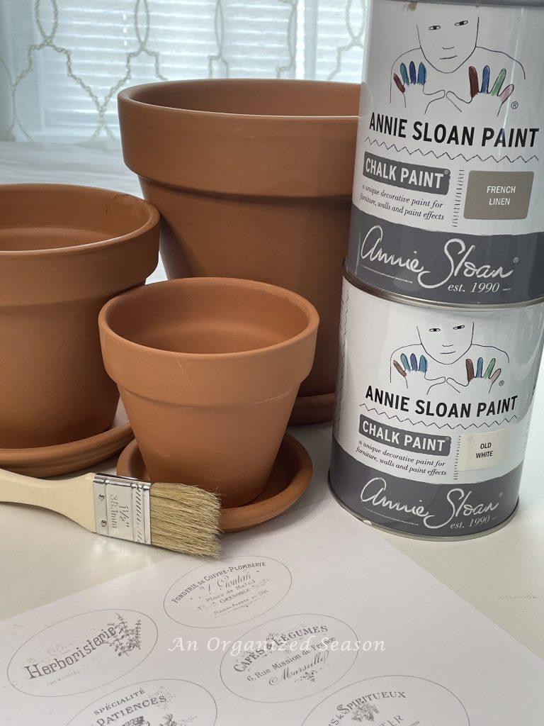Paint, pots, labels, and paintbrush. Items needed to age terra cotta pots & add French flair.