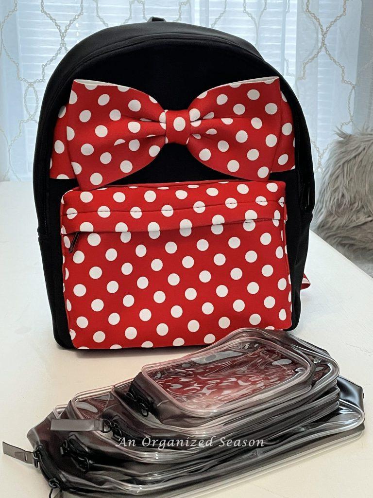 A Minnie Mouse backpack and plastic travel bags suggested for the amusement park ultimate packing list.