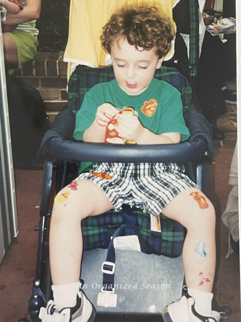 Boy in stroller with stickers shows suggestion from the amusement park ultimate packing list.