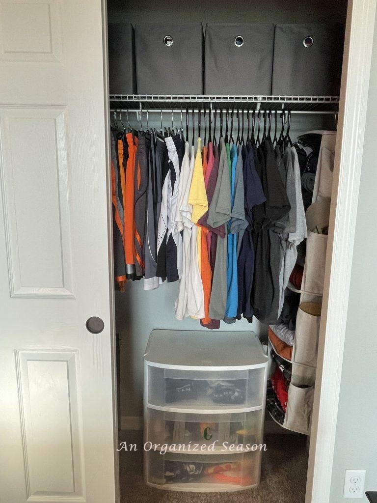Organized clothes in a closet showing how to teach your kid how to organize a closet.