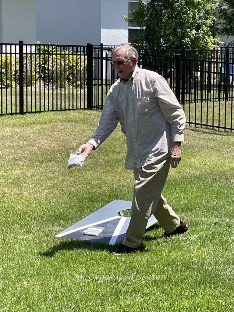 A dad playing cornhole in the backyard on Father's Day.