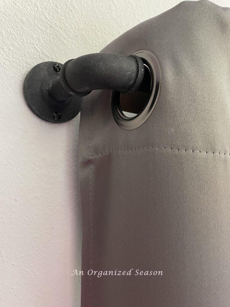 Black industrial curtain rod and gray curtains part of a boring bedroom makeover for a gamer.