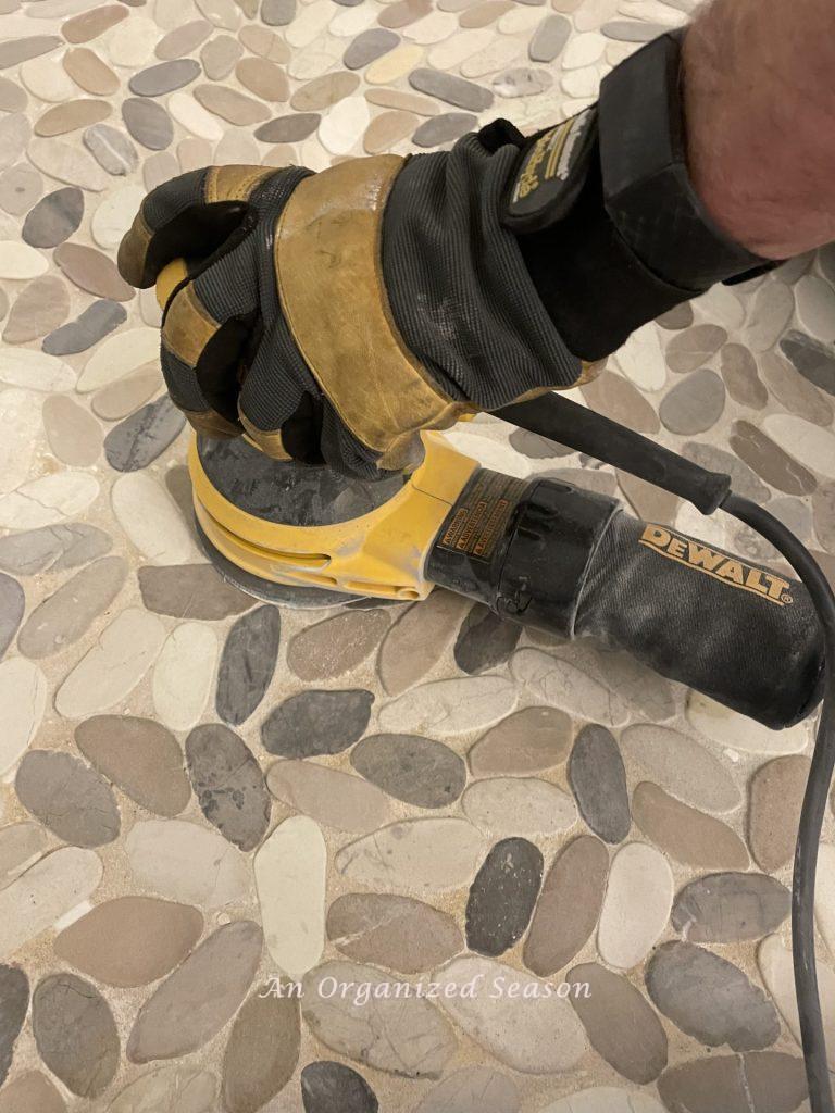 Sand the shower floor with a hand sander before you tile over the existing tile.