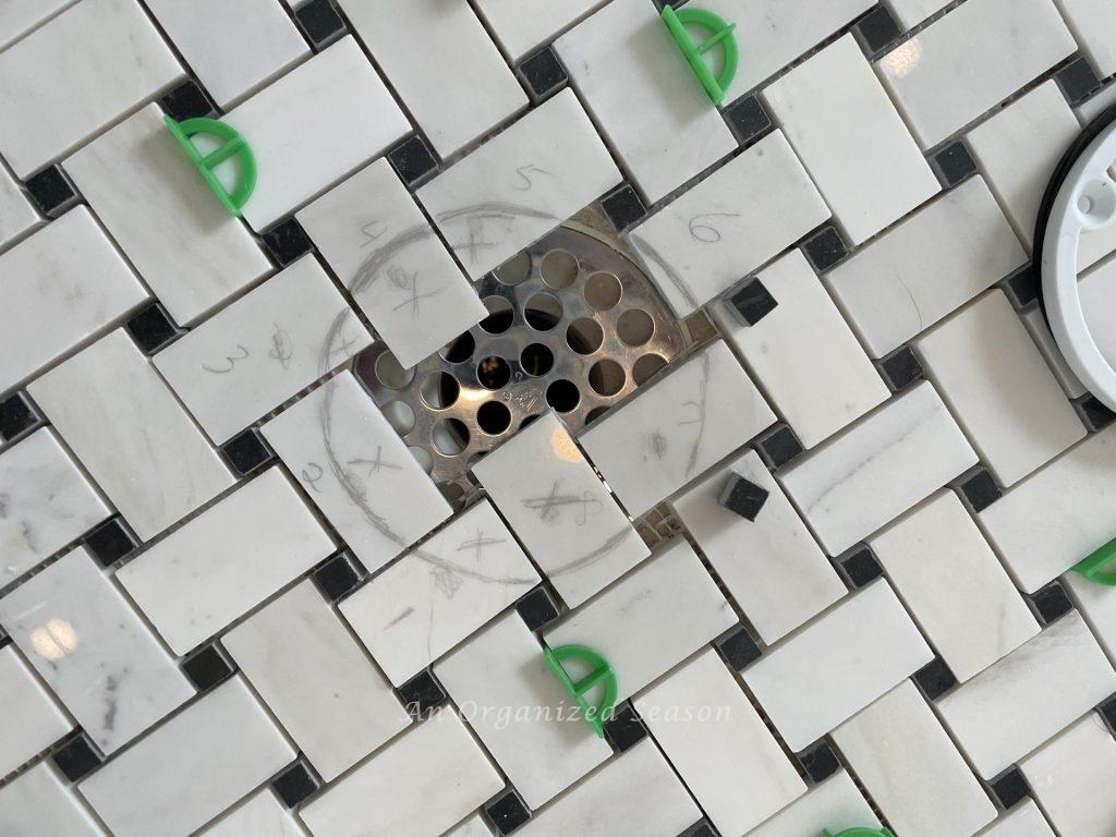 Mark the tiles to cut around the drain before you tile over the existing tile. 