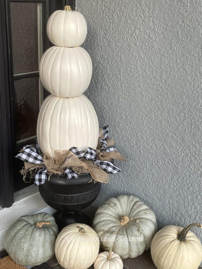 A pumpkin topiary made with 3 white pumpkins in a black flower pot is a fun DIY Fall decor craft project..