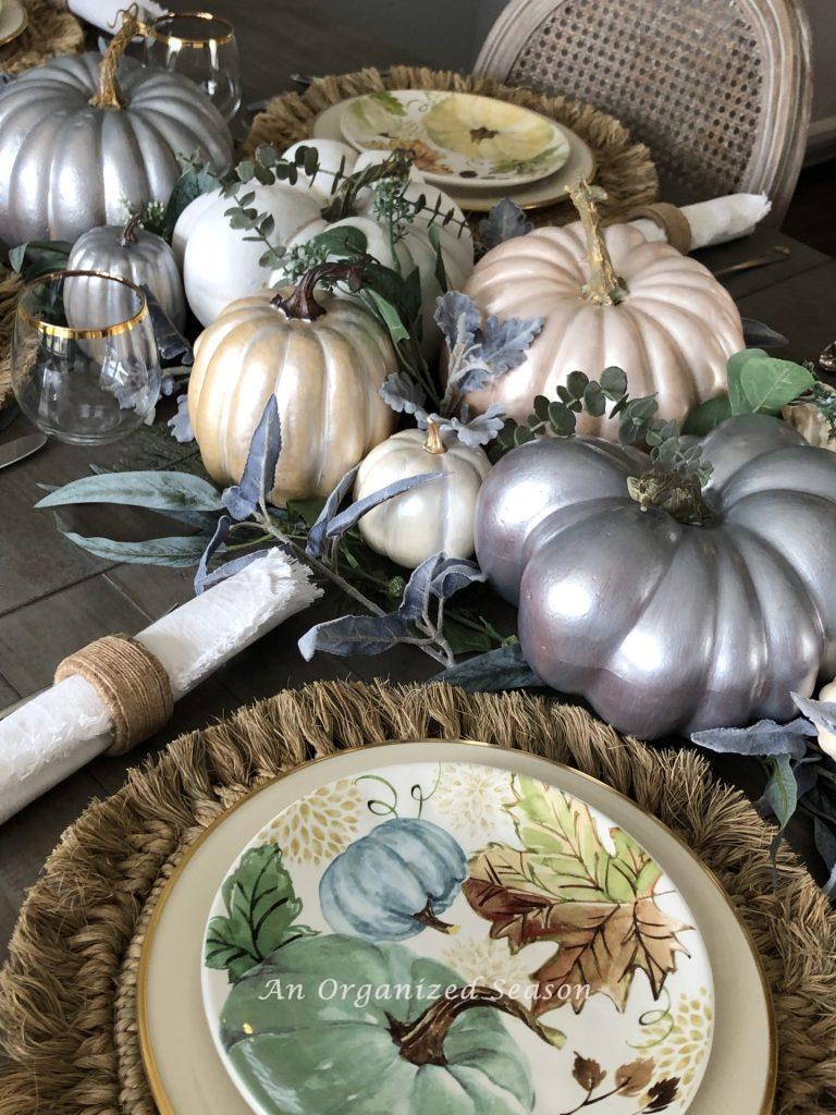 Six pearlescent painted pumpkins are a centerpiece on a table and would be a great DIY Fall decor craft to try!