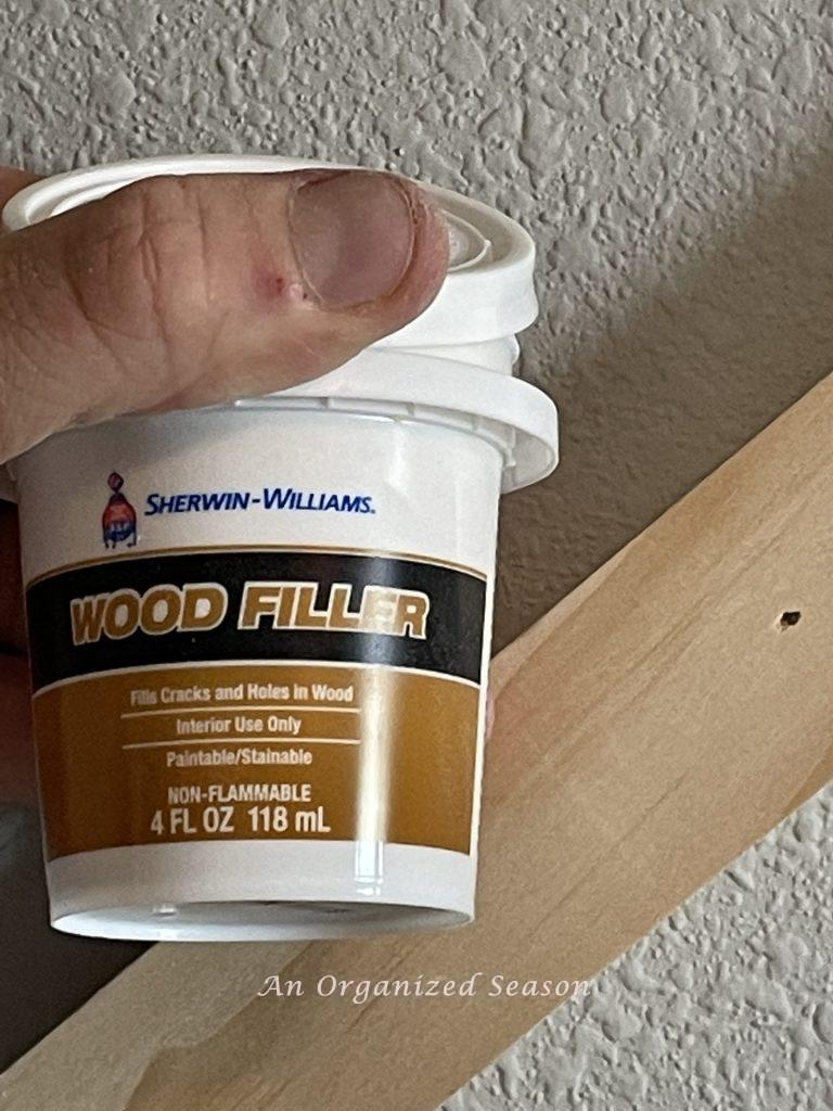 Wood filler used to fill nail holes, step four to build a modern accent wall in a bedroom.