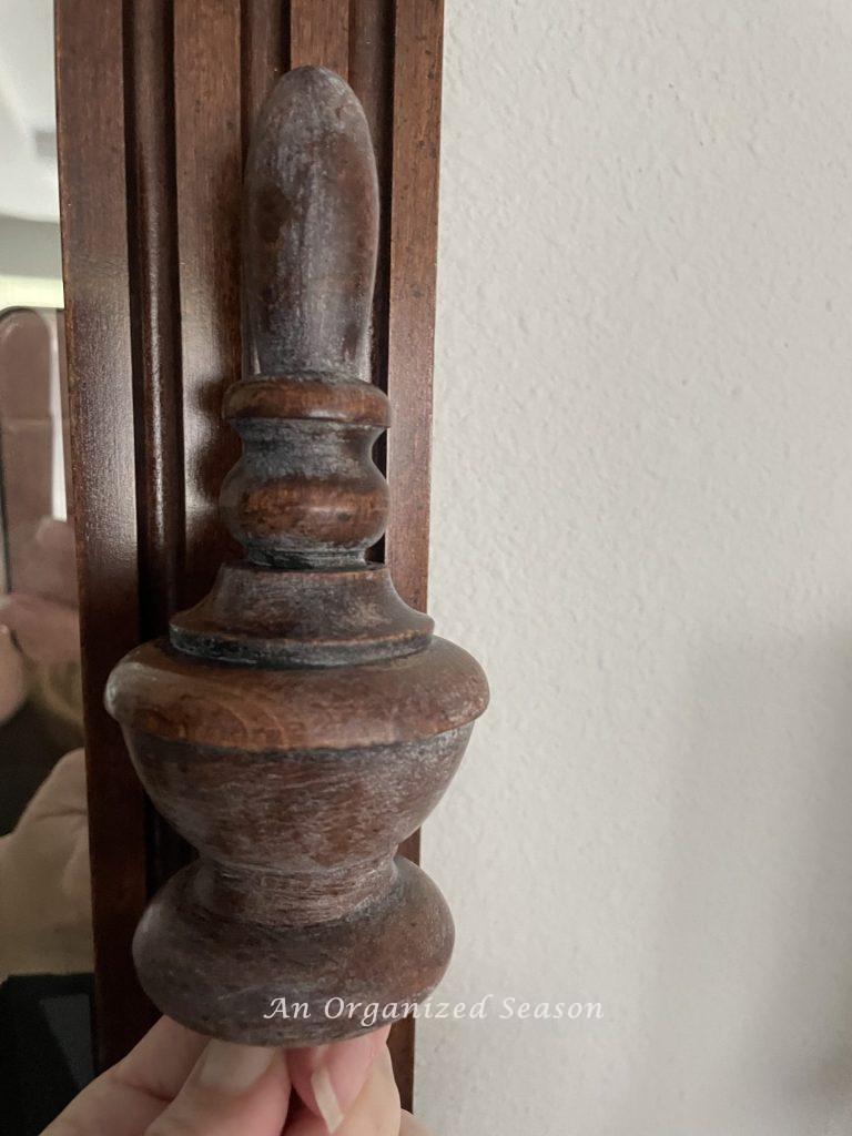 A wood finial with white haze on it, showing first attempt to strip and bleach wood furniture. 