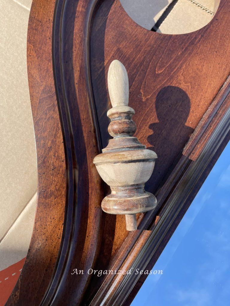 A wood finial that has been partially sanded to strip the stain off of it. 