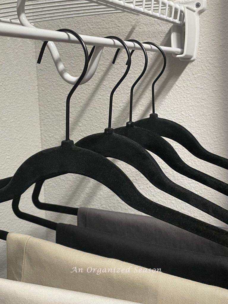 Black velvet matching hangers in an organized closet. 