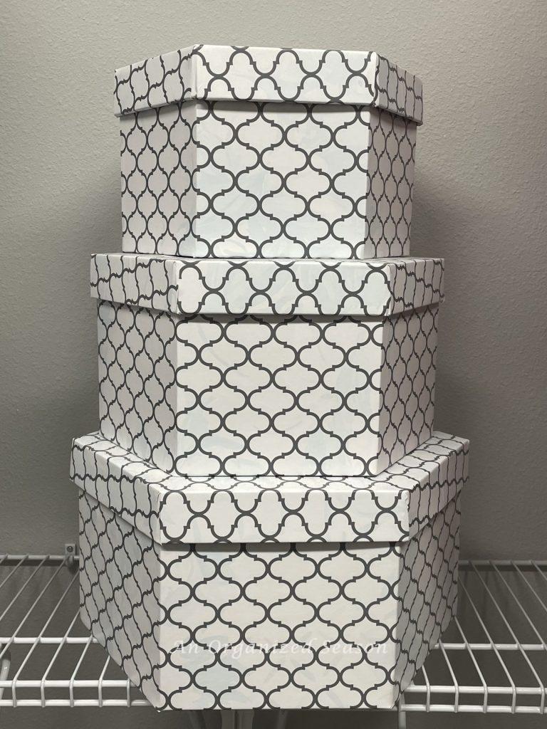 Three matching hat boxes store items in an organized closet. 