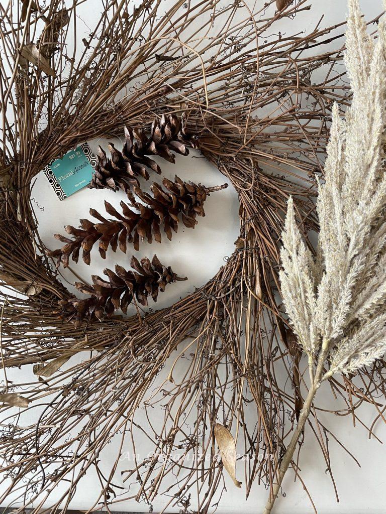 A twig wreath, three pinecones, and an off white spray of stems used to make a pinecone flower wreath