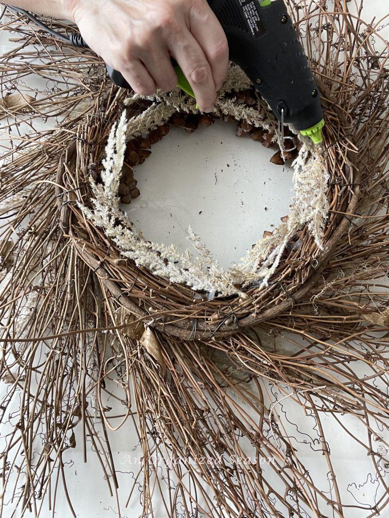 Hot gluing stems on the back of a pinecone flower wreath. 