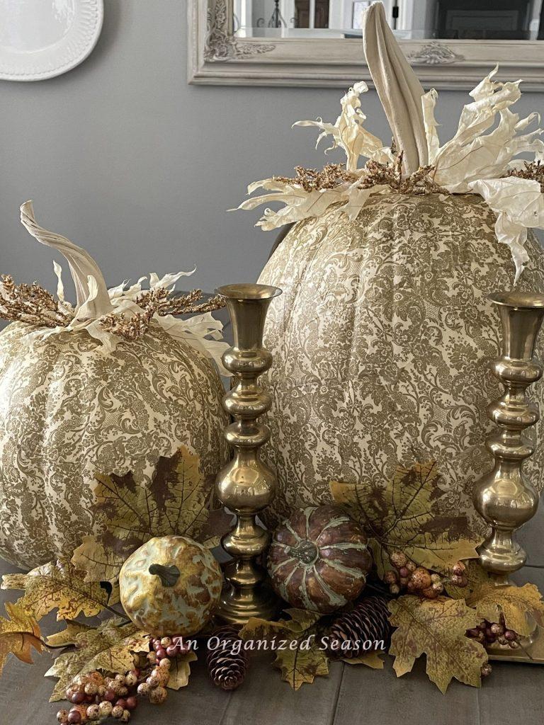 Two gold and white decoupage pumpkins decorate a dining room table. 