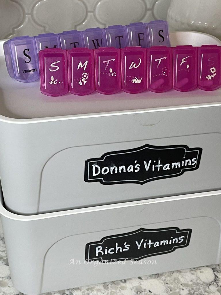 Two weekly pill box containers sitting on gray tubs, an example of how to organize medicine in your home.