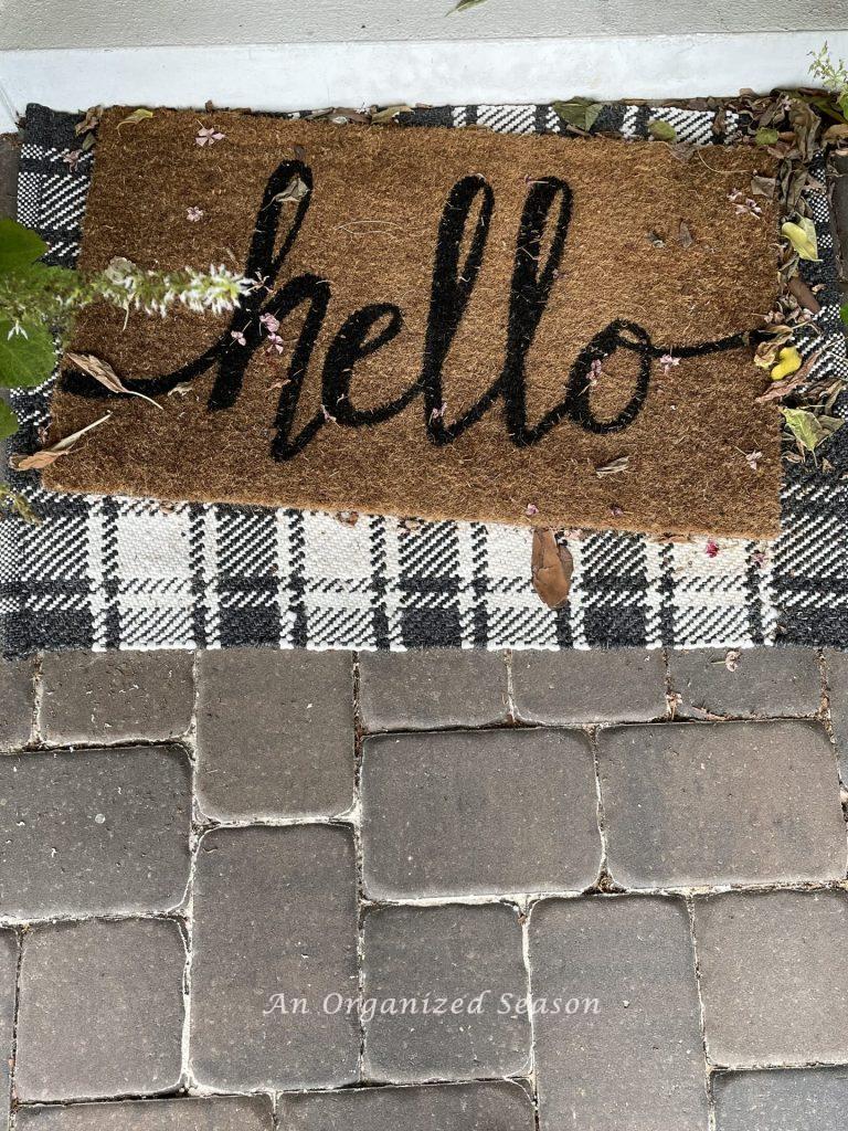 Welcome mat on front porch covered with leaves. 