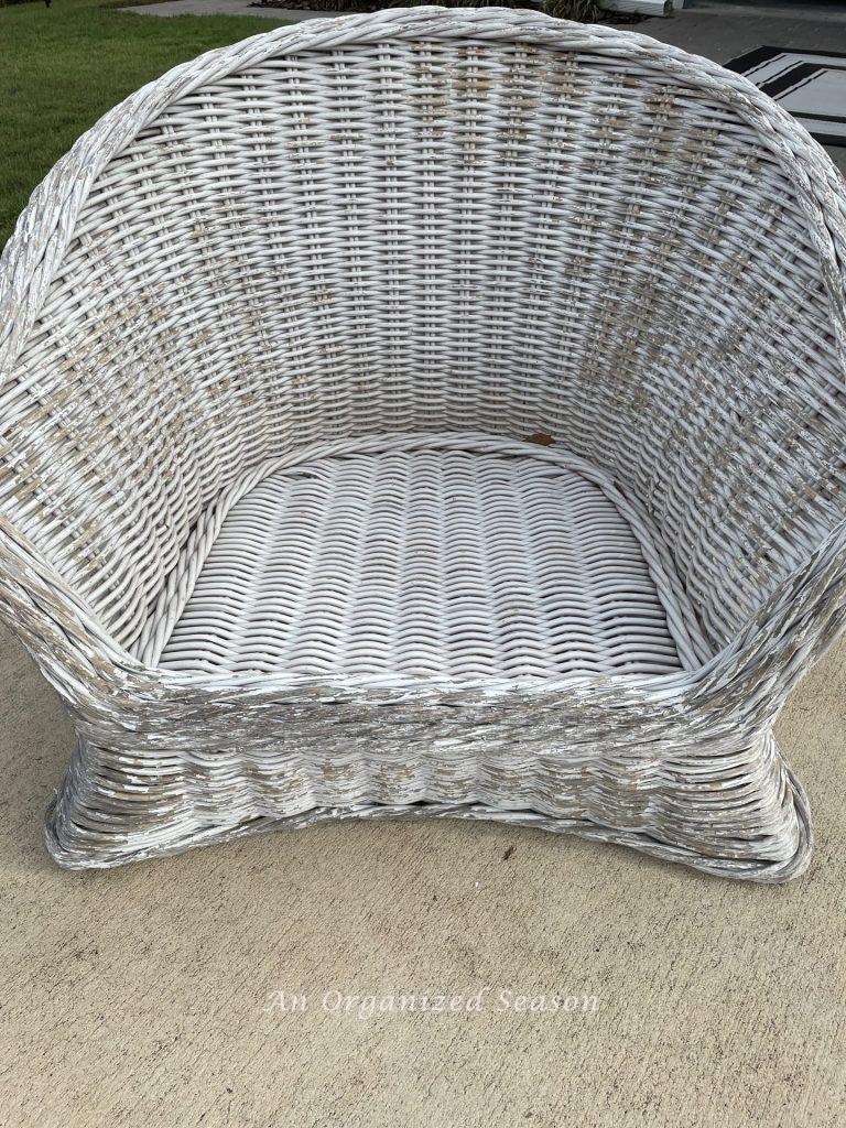 A rattan chair with peeling white paint. 