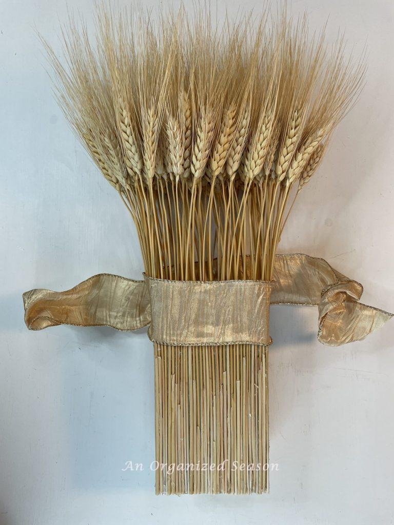 A dried wheat arrangement with a ribbon wrapped around it.  