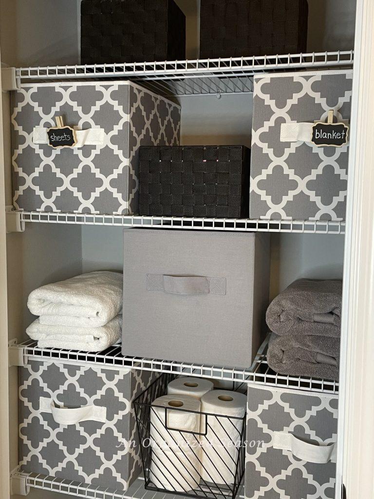 Fabric cubes storing items in an organized bathroom closet.