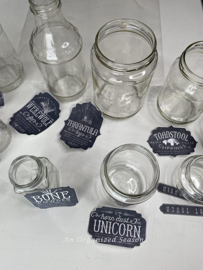 Empty jars and labels laying next to them, that will be used to make spooky potion bottles.