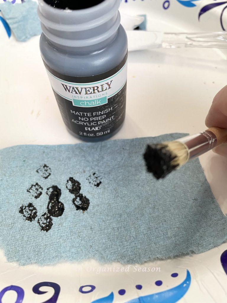 A small stencil brush dipped in black paint and blotted on a paper towel! 