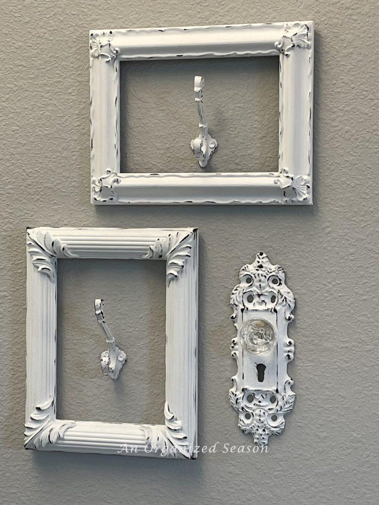 Two picture frames with hooks mounted inside them and a door knob used as towel hooks.